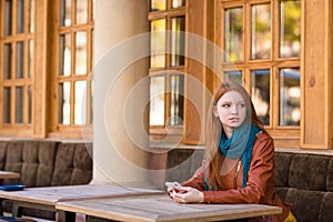 Pretty thoughtful woman sitting at the table in outdoor cafe