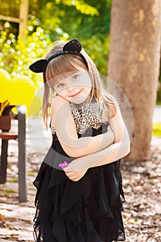 Pretty three year old girl in a cat costume, with a flower in her hand.