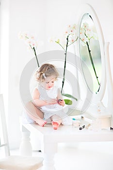Pretty toddler girl with curly hair playing with make up