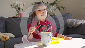 Pretty toddler girl eating at home with fork. Weekend morning breakfast