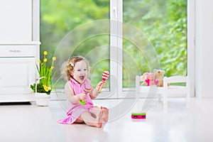 Pretty toddler girl playing maracas in white room photo