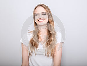 Pretty toothy laughing young woman with fair blond long hair in casual dress. Studio shot of good looking beautiful woman isolated