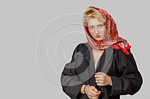 Pretty topless blonde girl in a black raincoat and colored scarf, hand near face, looking at camera