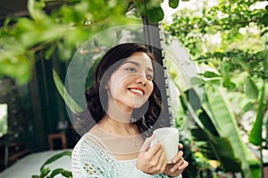 Pretty vietnamese woman enjoying her morning coffee on a veranda