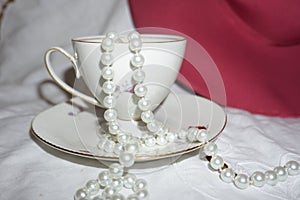 Pretty vintage teacup and saucer with pearl bead necklace spilling out