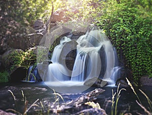 Pretty waterfall with slow shutterspeed for cascading water softening with a vintage retro instagram filter photo