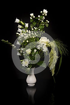 Pretty white flower bouquet in a white vase on a black background