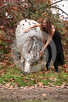 Pretty woman with appaloosa horse in autumn