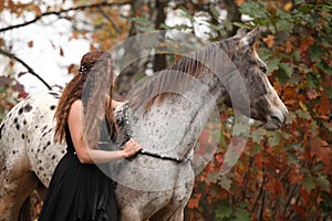 Pretty woman with appaloosa horse in autumn