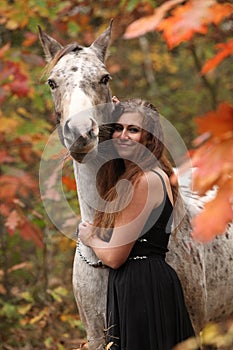 Pretty woman with appaloosa horse in autumn