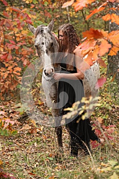 Pretty woman with appaloosa horse in autumn