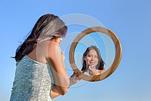 Woman applying lipstick makeup in mirror outside