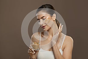 Pretty woman applying organic cream to her skin. Facial treatment and skin care concept