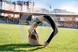 Pretty  woman athlete stretching her body at stadium grass
