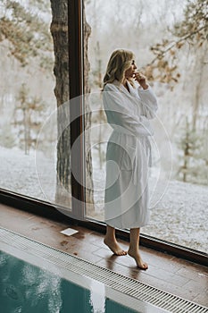 Pretty woman in bathrobe standing  by the pool in the spa