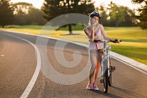 Pretty woman biker posing with bicycle outdoors.