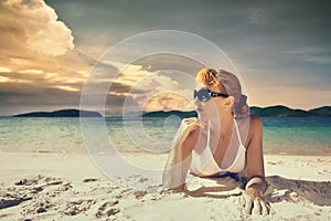 A pretty woman in bikini sunbathing at the beach on a background