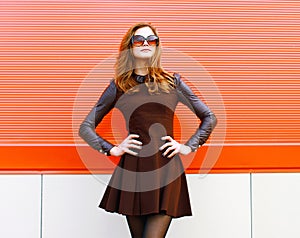 Pretty woman in black dress and sunglasses posing outdoors