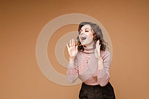 Pretty woman in black trousers and a fair shirt screams, picture isolated on yellow background