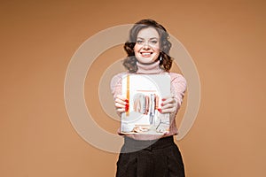 Pretty woman in black trousers shows an inteeresting book about fashion, picture isolated on yellow background