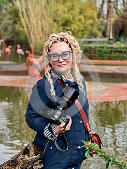 Pretty woman with blondy curly hair with a professional camera in hands