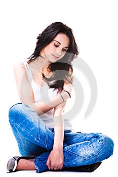 Pretty woman in blue jeans sitting on white floor