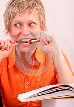 Pretty woman with book biting a pen