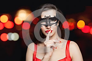 Pretty woman brunette model in black carnival mask on abstract night glitter bokeh background