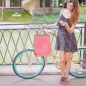 Pretty woman with bugs using mobile phone near vintage bicycle