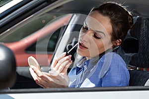 Pretty woman in a car doing makeup while standing in a traffic jam