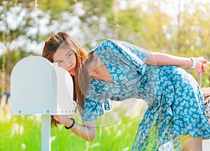 Pretty woman is checking her white mail box in a country farm house field