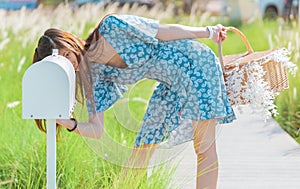 Pretty woman is checking her white mail box in a country farm house field