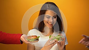 Pretty woman choosing salad instead of hamburger, healthcare vs junk food