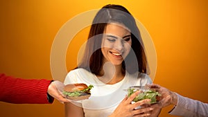 Pretty woman choosing salad instead of hamburger, healthcare vs junk food
