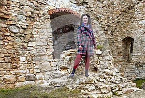 Pretty woman with curly hair stands on the ruins of an  medieval castle remains in Koknese