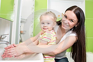 Pretty woman and daughter child girl washing hands with soap in bathroom