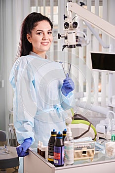 Pretty woman dentist in her office smiling, wearing uniform and gloves