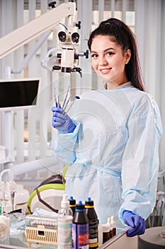 Pretty woman dentist in her office smiling, wearing uniform and gloves