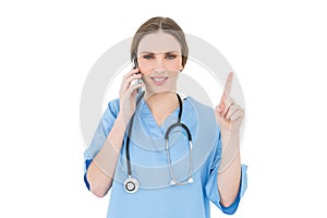 Pretty woman doctor phoning and pointing with her finger