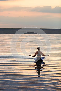 Pretty woman doing yoga at sunset outdoors