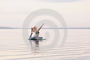 Pretty woman doing yoga at sunset outdoors