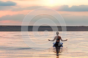 Pretty woman doing yoga at sunset outdoors