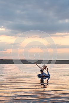 Pretty woman doing yoga at sunset outdoors