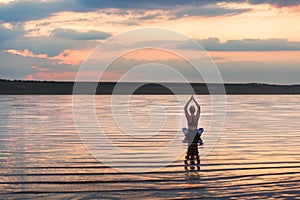 Pretty woman doing yoga at sunset outdoors