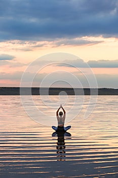 Pretty woman doing yoga at sunset outdoors