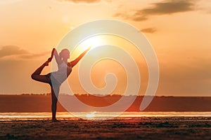 Pretty woman doing yoga at sunset outdoors