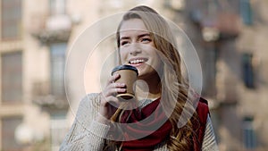 Pretty woman drinking coffee outdoors. Hipster girl enjoying hot drink on city