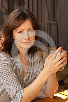 Pretty woman drinking coffee in sidewalk cafe. Brunette with morning coffee. Authentic lifestyle. Tranquil morning concept.