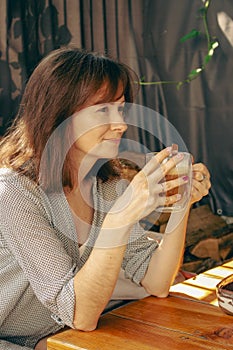 Pretty woman drinking coffee in sidewalk cafe. Brunette with morning coffee. Authentic lifestyle. Tranquil morning concept.