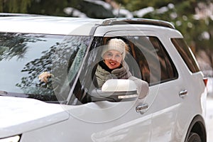 Pretty woman driving a white car in winter forest